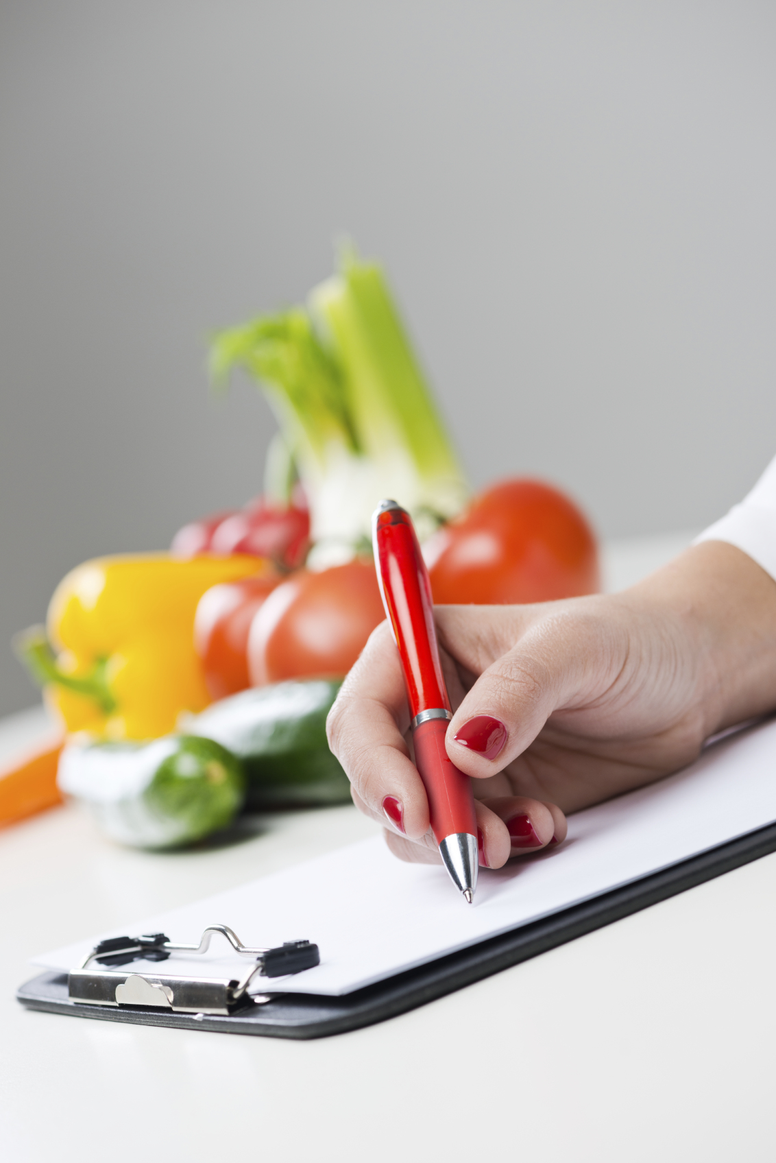 Nutritionist writing medical records and prescriptions with fresh vegetables